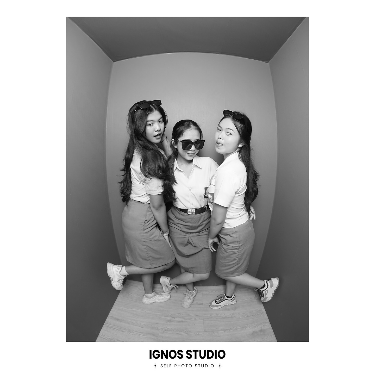 Tiga siswi SMA berpose keren menggunakan kacamata hitam di dalam photo box dengan lensa wide-angle (fisheye) hitam putih di Ignos Studio Bali.