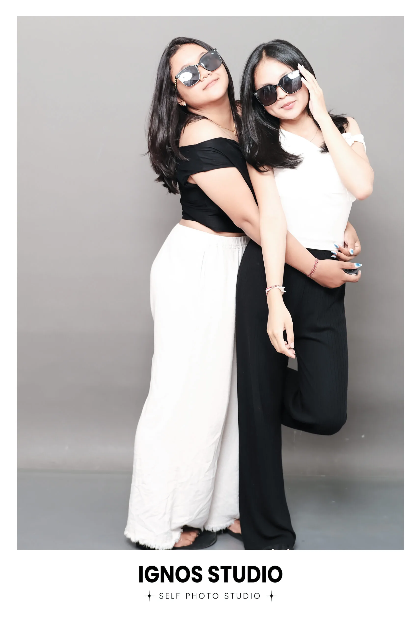 Dua wanita berpose modis menggunakan kacamata hitam di Ignos Studio untuk sesi foto lifestyle atau sahabat.