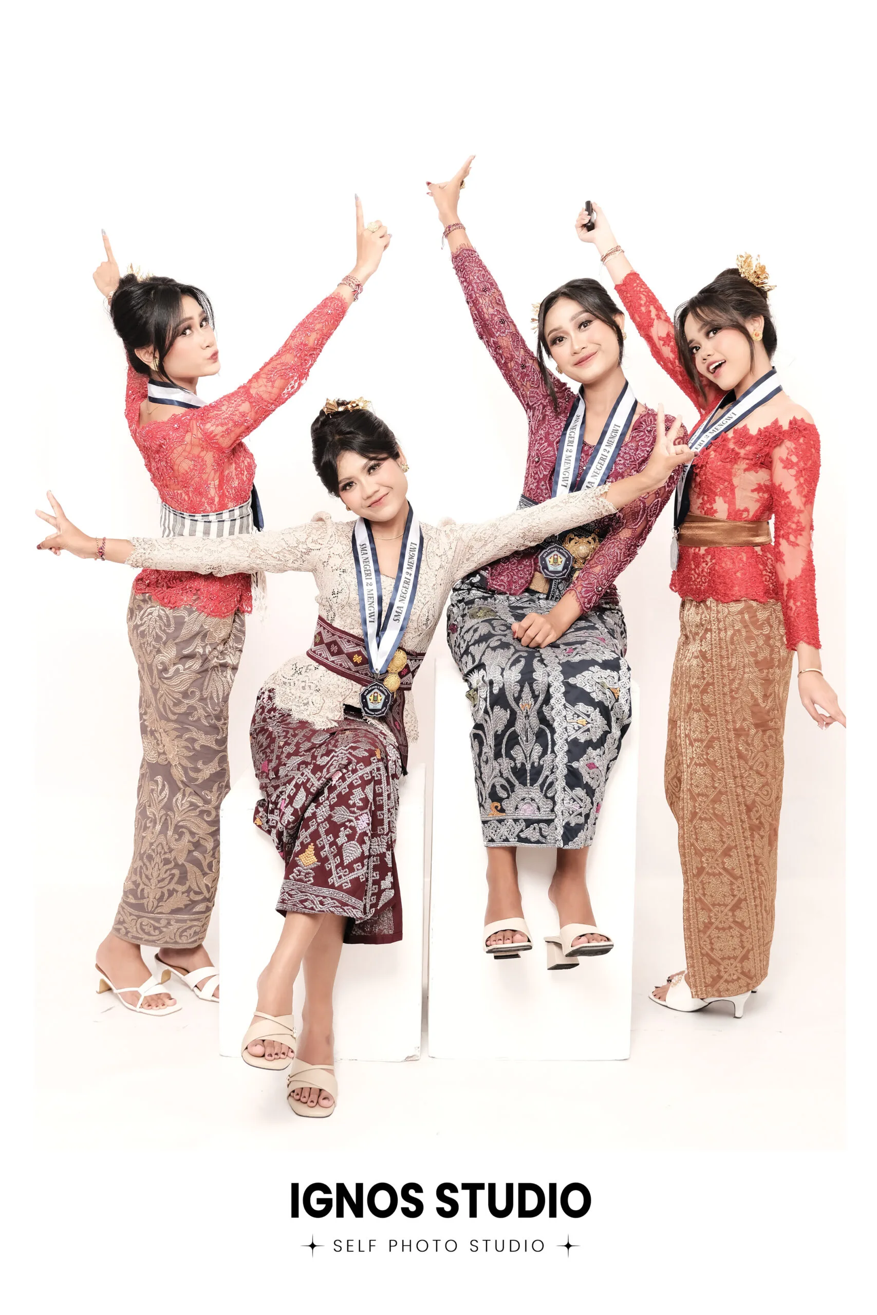 Grup wanita mengenakan kebaya tradisional berwarna merah dan krem berpose ceria di Ignos Studio untuk sesi foto kelulusan atau bridesmaid.