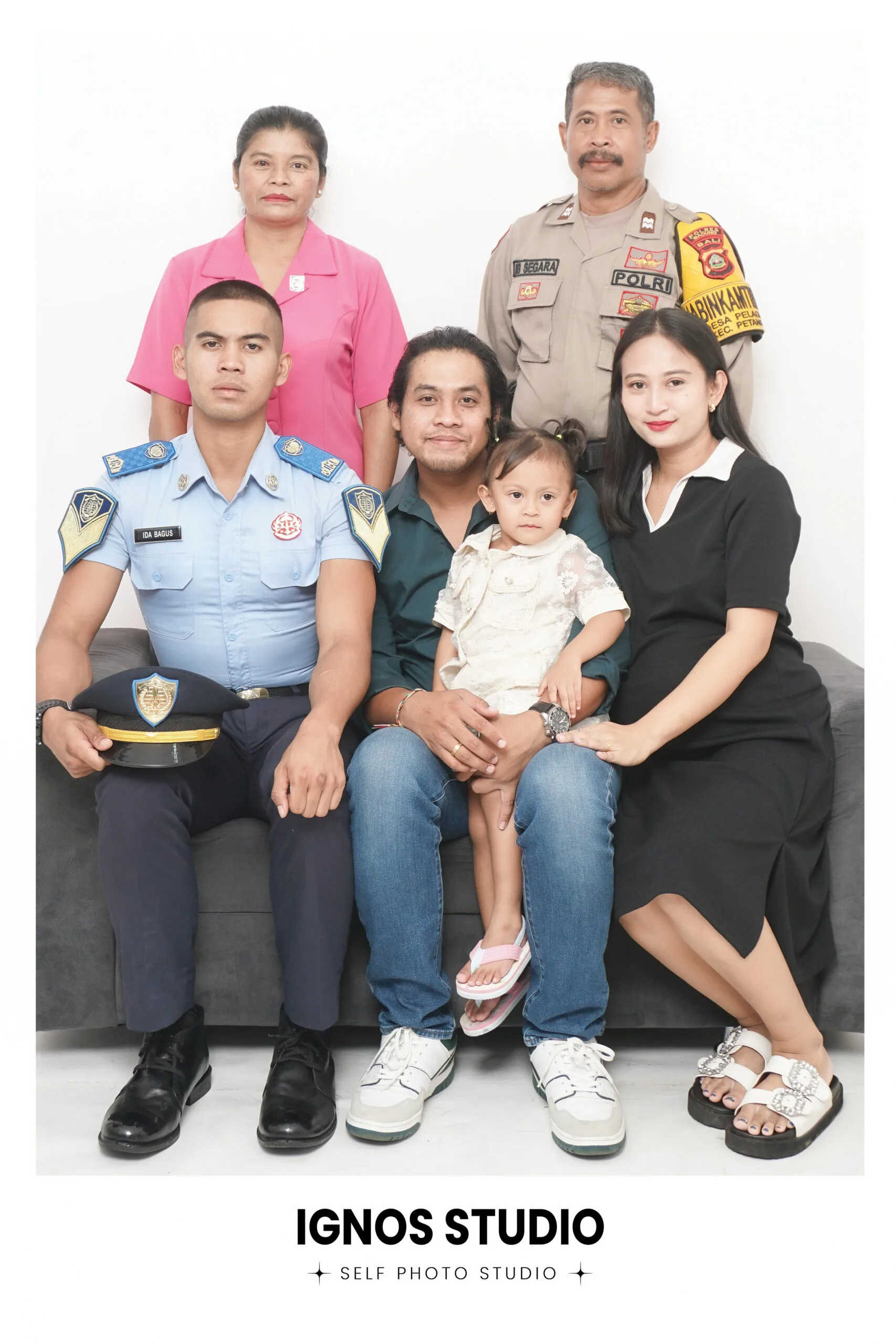 Foto keluarga besar di Ignos Studio menampilkan anggota keluarga dengan seragam dinas Polri, Dinas Perhubungan, dan pakaian kasual.