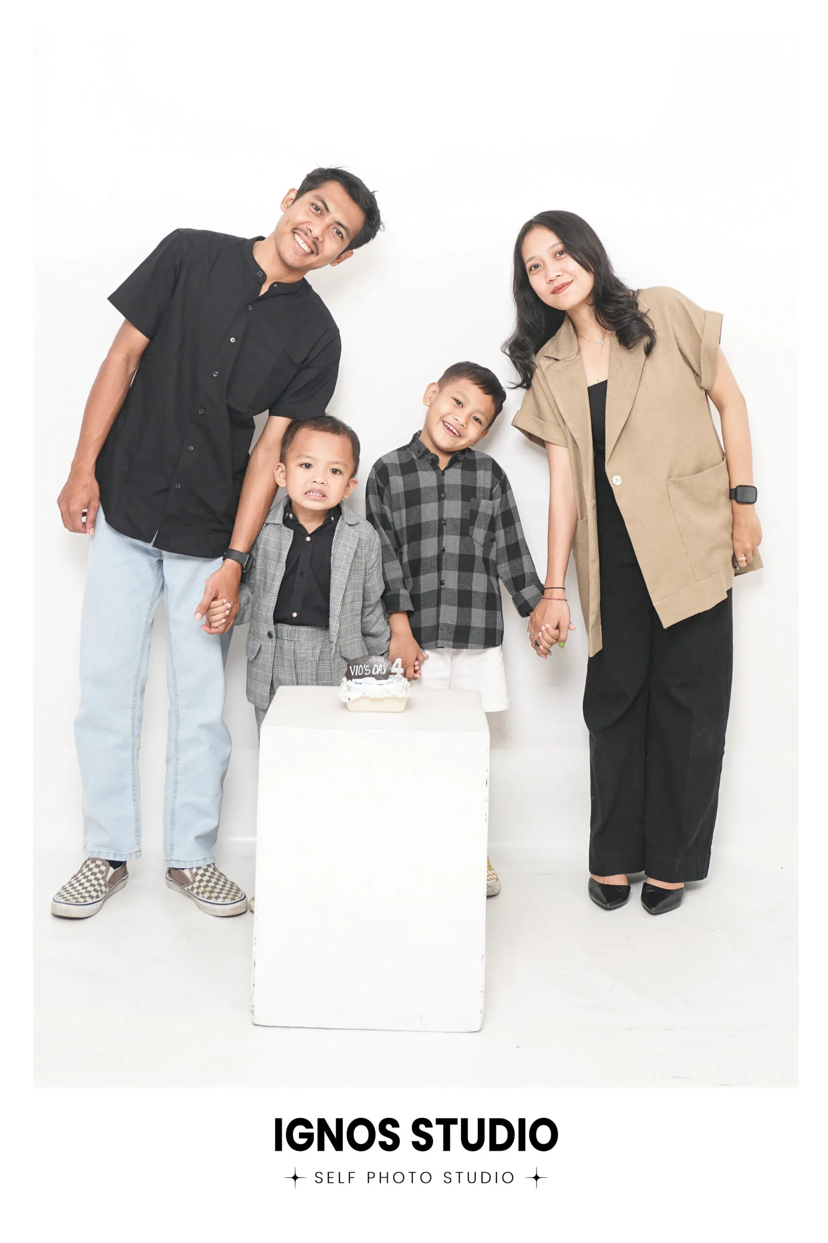 Foto keluarga inti (ayah, ibu, dan dua anak laki-laki) dengan busana kasual minimalis di Ignos Studio.