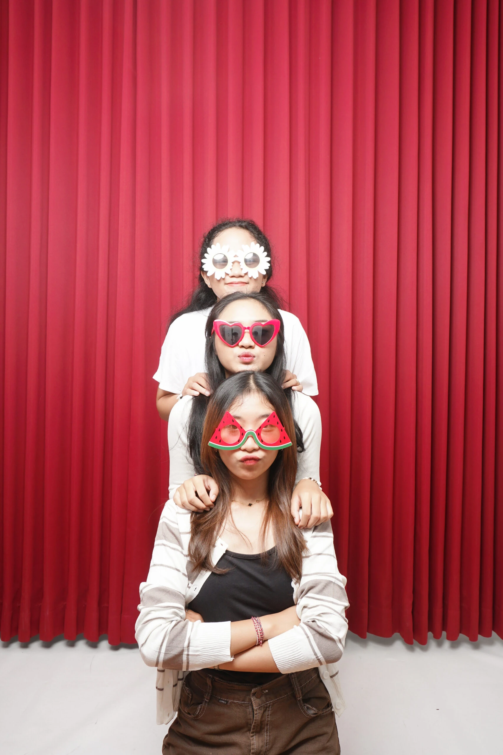 Tiga wanita berpose unik dengan latar belakang merah di Ignos Studio - Self Photo Studio.