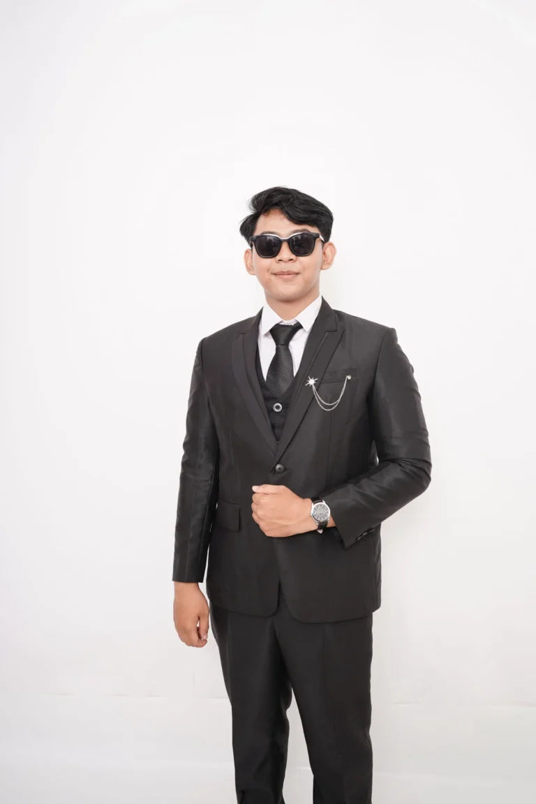 Seorang pria mengenakan setelan jas hitam formal (suit), rompi, dasi, dan kacamata hitam dari layanan sewa jas Ignos Suit di Bali.